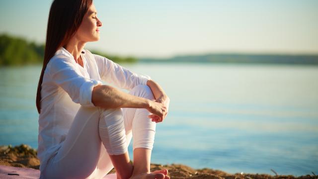 Mujer sentada frente al mar en una actitud relajada