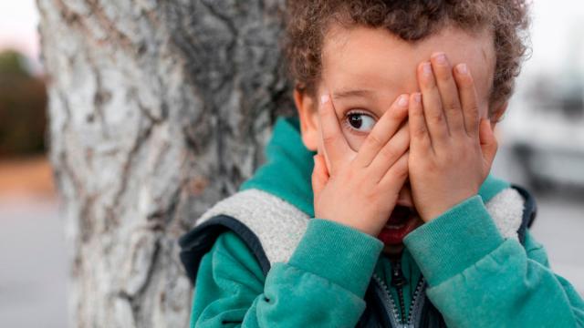 Niño tampándose la cara con las manos